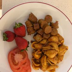 A picture of Jollof pasta shells and sausage.