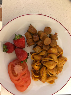 A picture of Jollof pasta shells and sausage.