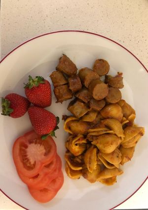 A picture of Jollof pasta shells and sausage.