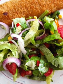 Una foto de Milanesa de pescado al horno con ensalada multicolor