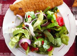 Una foto de Milanesa de pescado al horno con ensalada multicolor