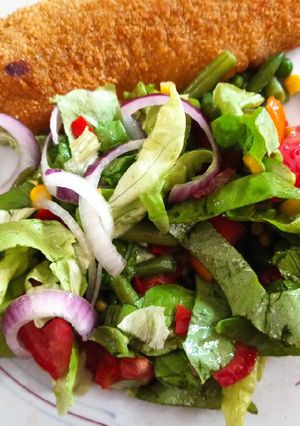 Una foto de Milanesa de pescado al horno con ensalada multicolor