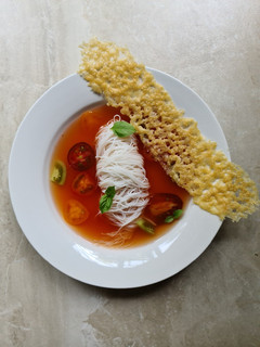 A picture of Tomato broth with vermicelli noodles and parmesan crisp.