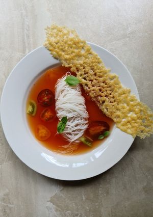 A picture of Tomato broth with vermicelli noodles and parmesan crisp.