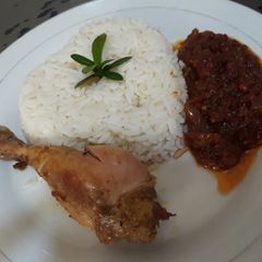 A picture of Boiled rice with tomato stew and chicken.