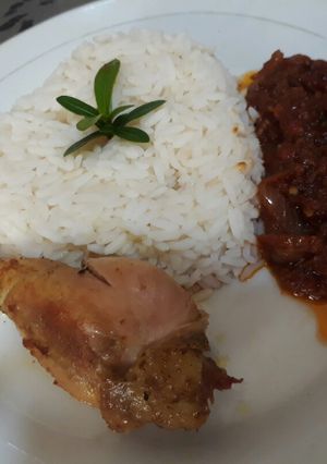 A picture of Boiled rice with tomato stew and chicken.