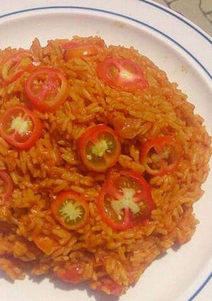 A picture of Jollof rice with fresh sliced tomatoes.