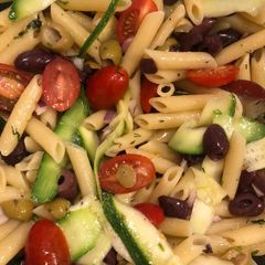 A picture of Penne pasta salad with zucchini and olives.