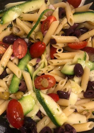 A picture of Penne pasta salad with zucchini and olives.
