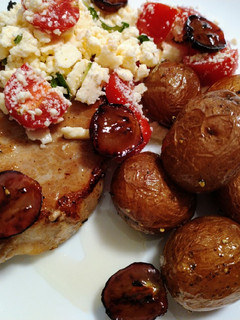 A picture of Baked pork chop, feta, tomato, honey, truffled potatoes & grapes.