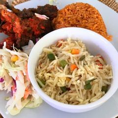 A picture of Jollof rice, fried rice, peppered chicken and coleslaw.