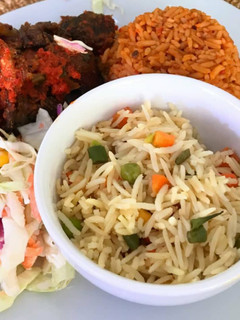 A picture of Jollof rice, fried rice, peppered chicken and coleslaw.