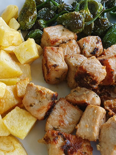 Una foto de "Raxo a Galega" con pimientos de Padrón y patatas fritas
