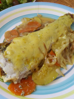 Una foto de Merluza al horno en cama de zanahoria, zapallitos y cebolla caramelizada
