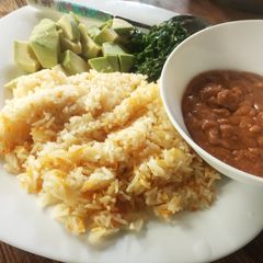 A picture of Carrot cumin rice served with peanut sauce and veggies.