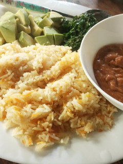 A picture of Carrot cumin rice served with peanut sauce and veggies.