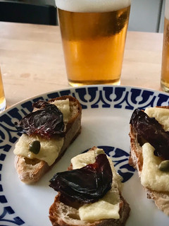 Una foto de Tosta de queso curado con ciruela deshidratada y alcaparras