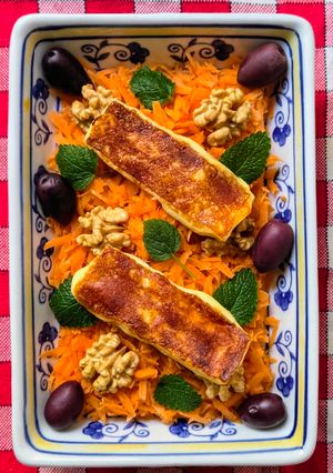 Una foto de Queso Halloumi grillado, sobre colchón de zanahoria con nueces, menta y aceitunas Kalamata 🧀🫒🥕🌱