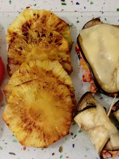 Una foto de Canelones de berenjenas rellenos de carne, frutas y verduras con piña asada y tomate rosa