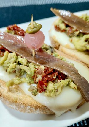 Una foto de Tosta de scamorza ahumada y anchoa con aguacate y tomate seco