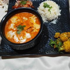 A picture of Handi paneer with boiled rice, aloo gobhi and salad.