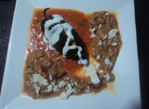 Una foto de Chile relleno de totopos entomatados y pollo, con frijoles con pelo de ángel de chile, las Correa