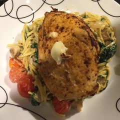 A picture of Stuffed chicken on a bed of creamy cheesy noodles.