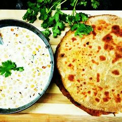 A picture of Alu paneer paratha serve with boondi raita.