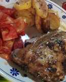 Pollo al horno con papas al horno y una ensalada de tomate