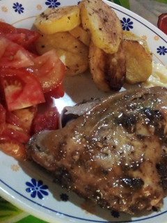 Una foto de Pollo al horno con papas al horno y una ensalada de tomate