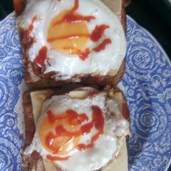 A picture of Sausage, egg, bacon and cheese sandwich with hot sauce.