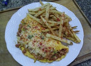 Una foto de Chistorra con huevo, cebolla caramelizada y papas fritas