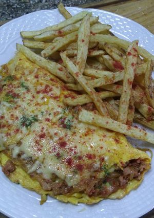 Una foto de Chistorra con huevo, cebolla caramelizada y papas fritas