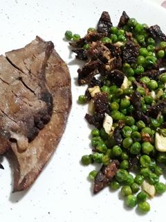 Una foto de Hígado de cerdo con salteado de guisantes, dientes de ajo tomate