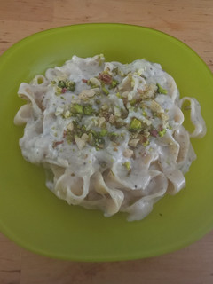 Una foto de Tagliatelle cocidos en crema de soja + cebolleta, ajo, parmesan, decorados con pistachos y anacardos