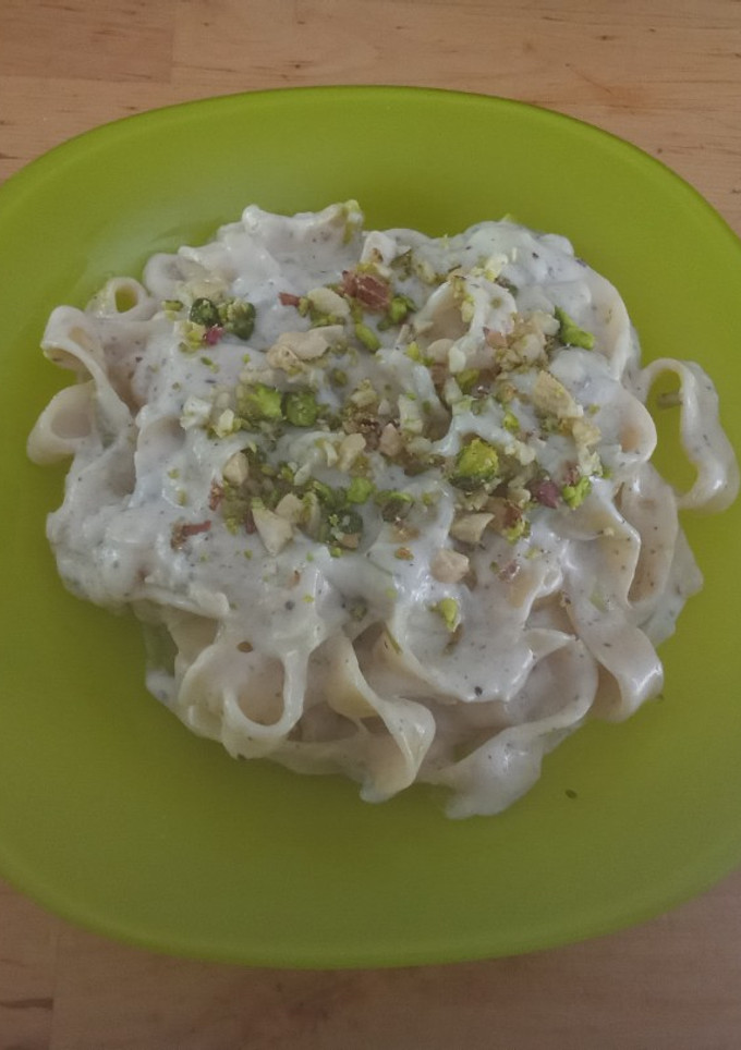 Una foto de Tagliatelle cocidos en crema de soja + cebolleta, ajo, parmesan, decorados con pistachos y anacardos