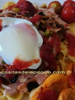 Una foto de Pappardelle con sofrito de tomatitos cherri, ajo negro y pistachos, acompañado de huevo a baja temperatura