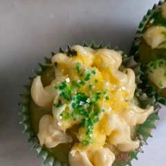 A picture of Vanilla cupcakes with vanilla frosting and sugar sprinkle.
