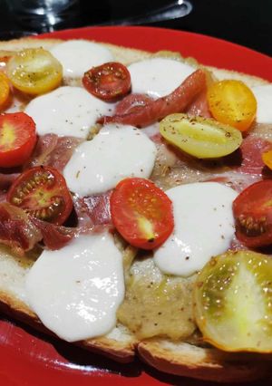 Une photo de Bruschetta caviar d'aubergines, tomates cerises, jambon cru et mozzarella