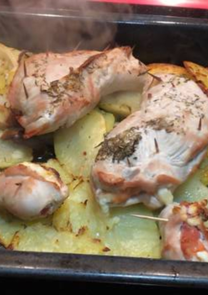 Una foto de Solomillo de pavo relleno de jamón serrano y queso sobre cama de patatas y cebolla