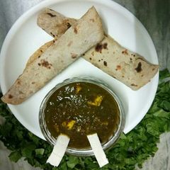 A picture of Palak paneer with roti roll.