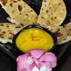 A picture of Oats Paneer stuffed coin paratha with Aamras.