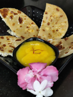 A picture of Oats Paneer stuffed coin paratha with Aamras.