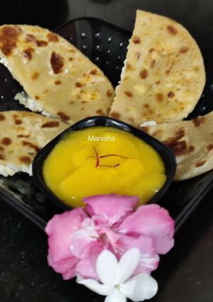 A picture of Oats Paneer stuffed coin paratha with Aamras.