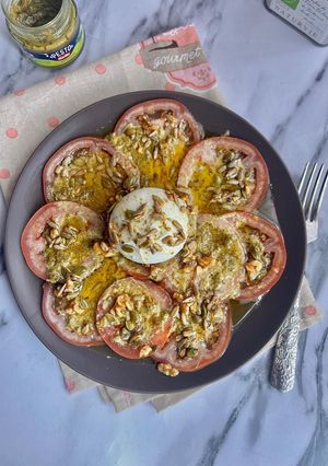 Una foto de Carpaccio de tomates con pesto y burrata