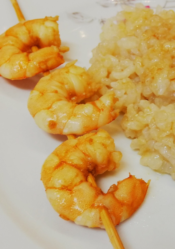 Una foto de Brochetas de langostinos marinados y arroz en salsa de soja