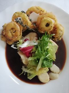 Una foto de Ensalada de bacalao sobre caramelo de tomate y aros de cebolla