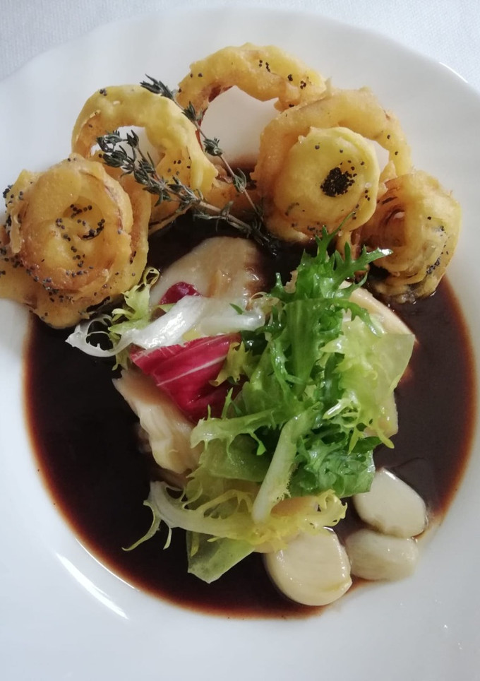 Una foto de Ensalada de bacalao sobre caramelo de tomate y aros de cebolla