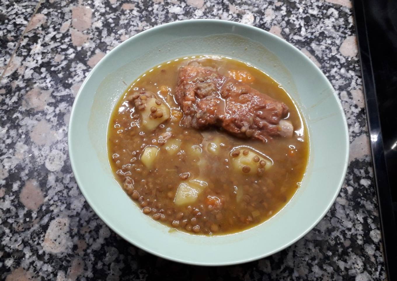 Lentejas con costillas adobadas, espinazo y manitas de cerdo