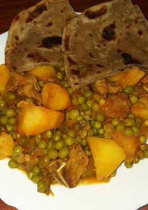 A picture of Beef stew with potatoes and green peas.